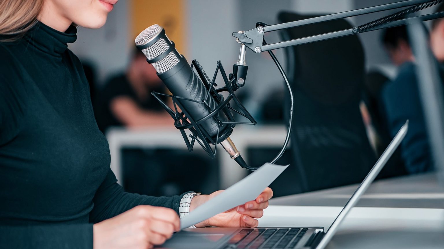 Une personne face à un micro enregistrant un podcast © iStock