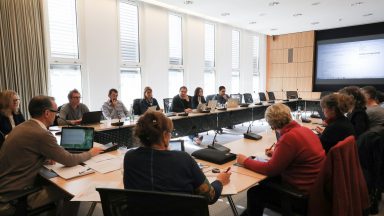 Séance de travail de l'Assemblée d'École. Plusieurs personnes assises autour d'une table en U