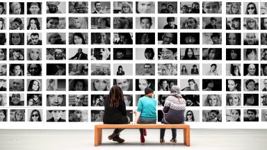 Des personnes dans un musée, assises face à une série de photos