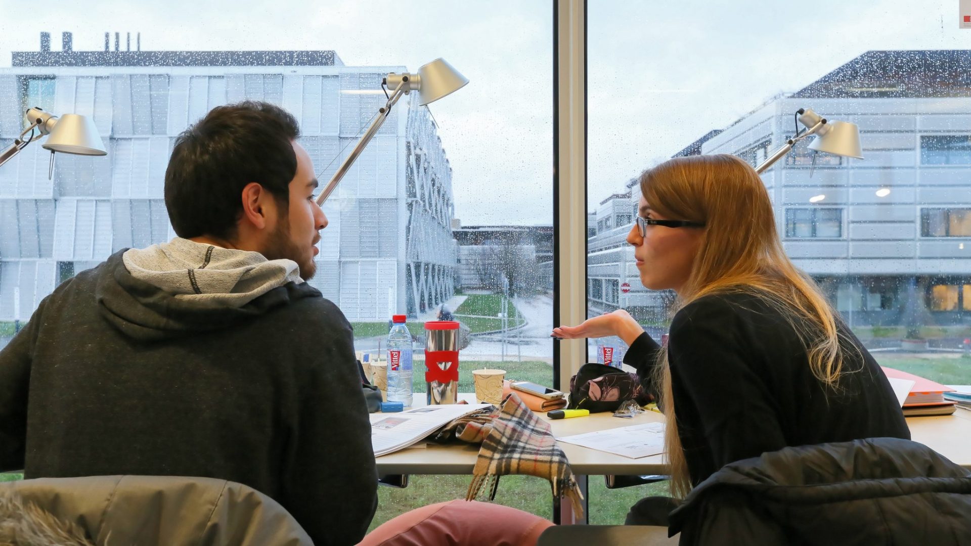 Des étudiants discutant devant une fenêtre du Rolex Learning Center, en révisant leurs examens