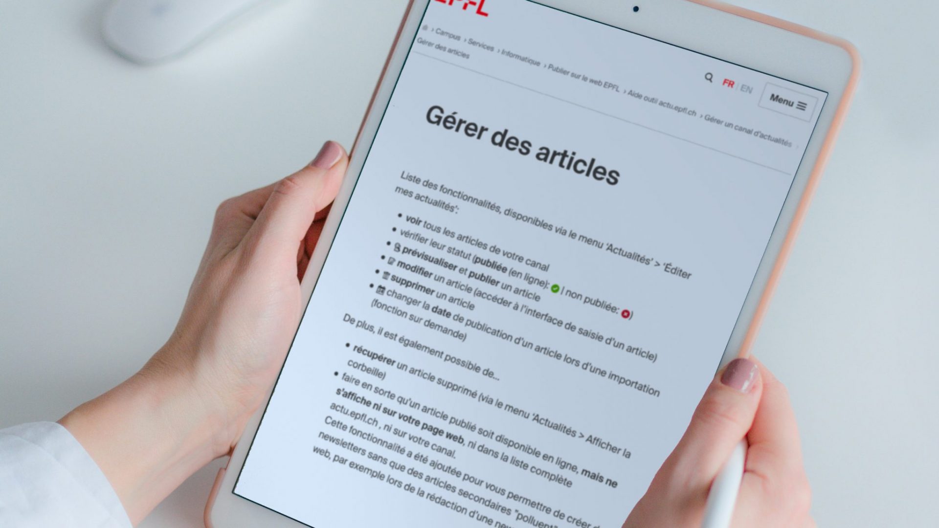 Une personne tenant une tablette avec une page d'aide de l'EPFL