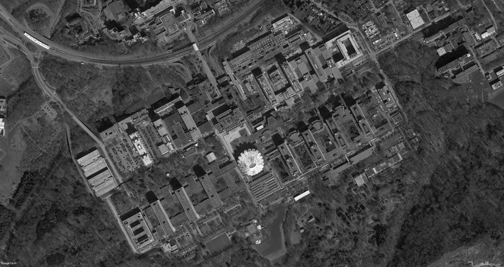 La vue aérienne montre la distribution des bâtiments en deux rangées le long d’un axe longitudinal.