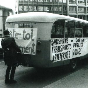 Deux étudiants accrochent contre un bus des banderoles avec des slogans. Ils revendiquent une meilleure liaison entre Lausanne et Dorigny.