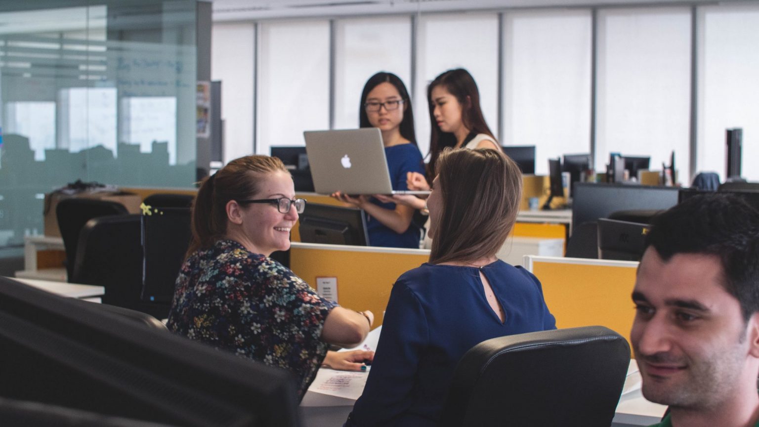 People smiling at their computer in an open-plan office space