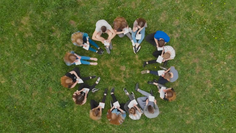 Students in a circle sitting on grass